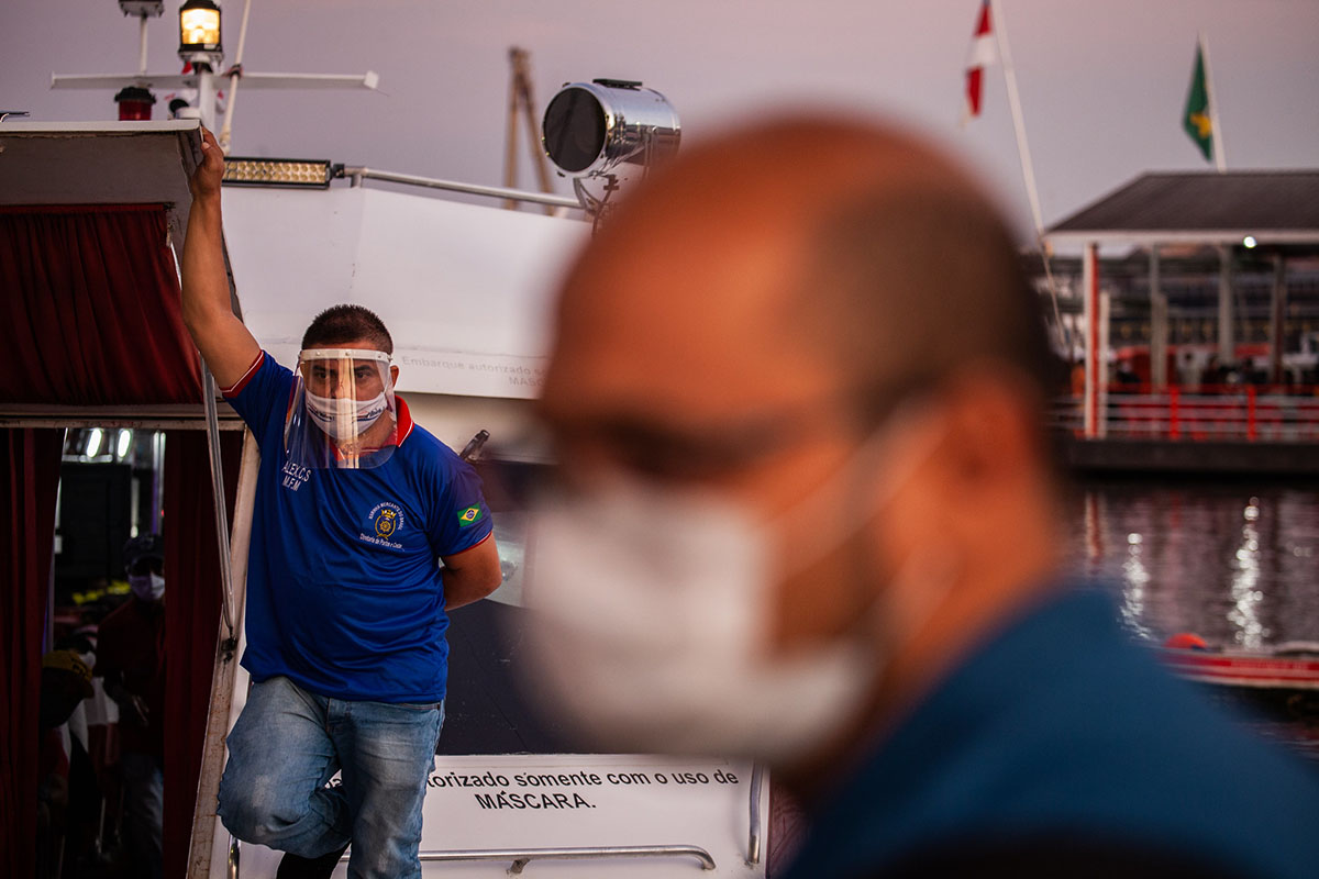 A passenger wearing protective equipment awaits the departure of a speedboat in Manaus, Brazil in 2020. IMF / Raphael Alves 