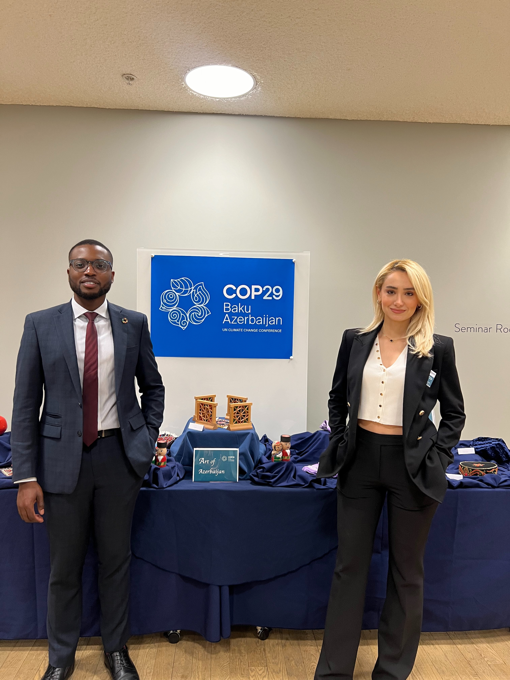 Kay Atanda and Laman in from of COP29 poster