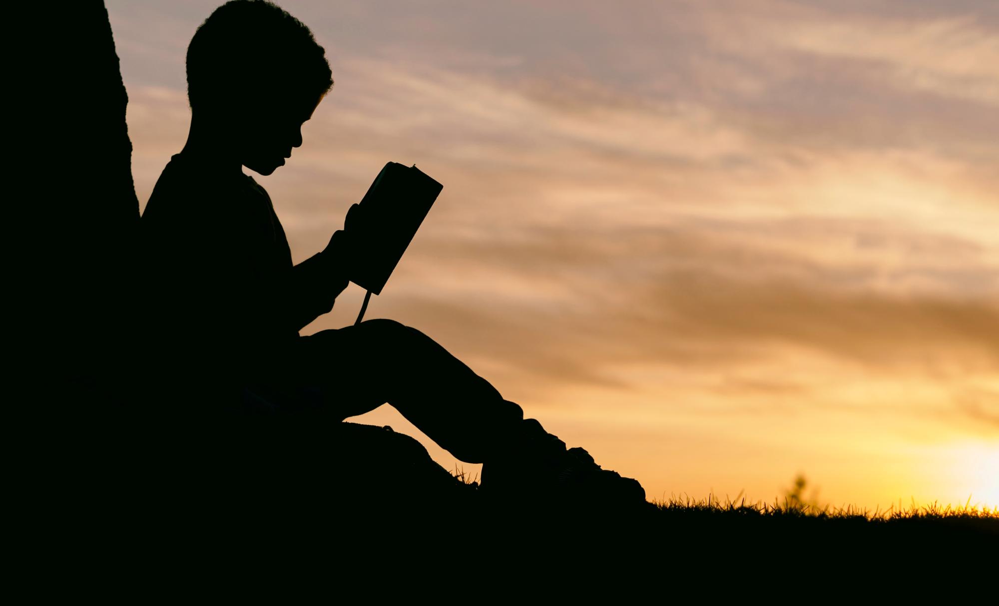 Child in silhouette reading