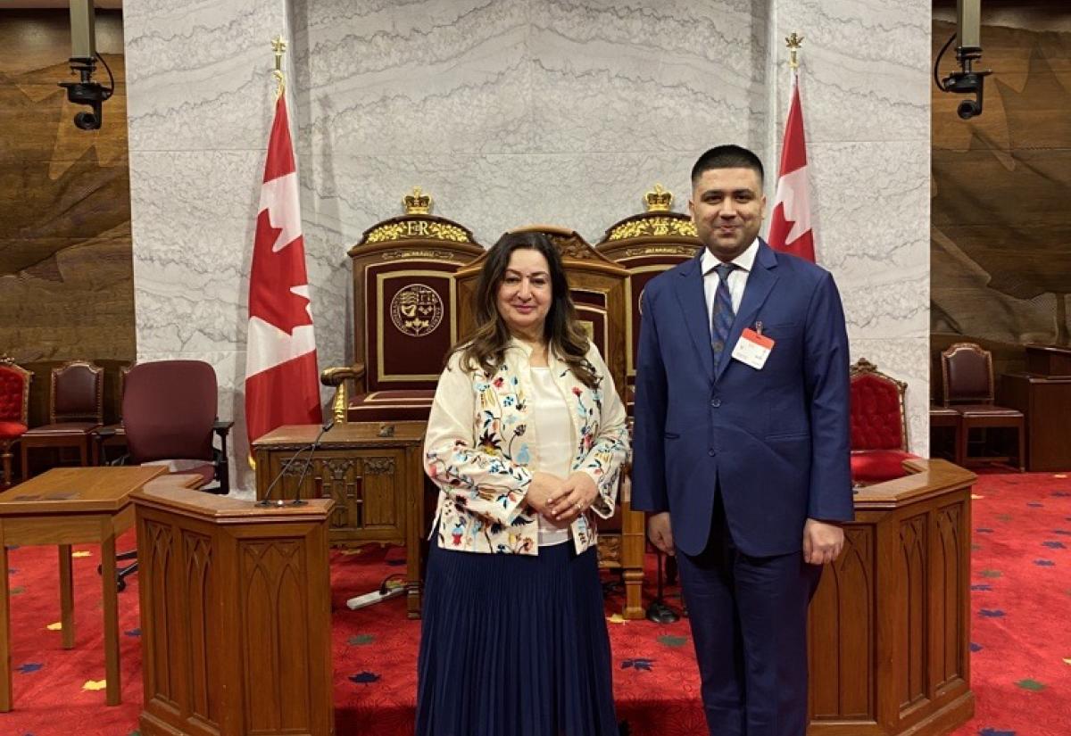 Blavatnik School alumnus Shoaib Rizvi stands next to the Canadian Senator Salma Ataullahjan with a background of the Canadian flags